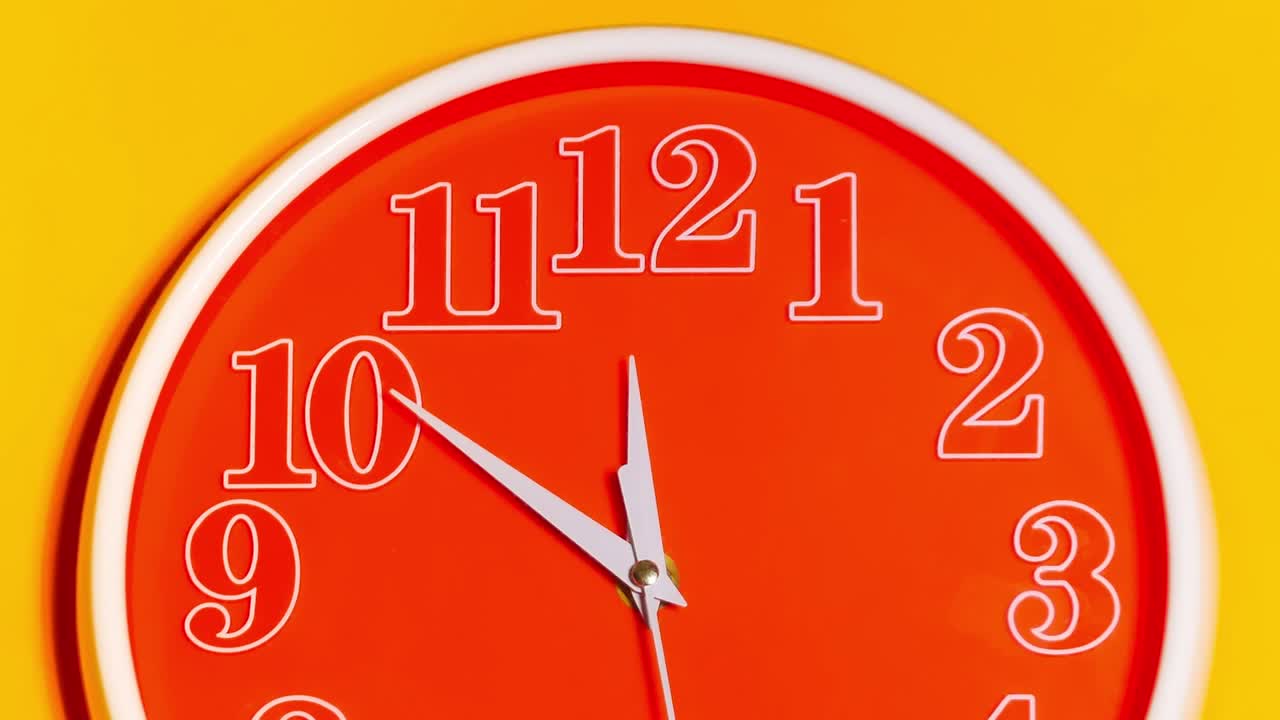 Zoom out of modern orange clock face beginning of time 11.43 on yellow background, Time lapse 45 minutes moving fast.