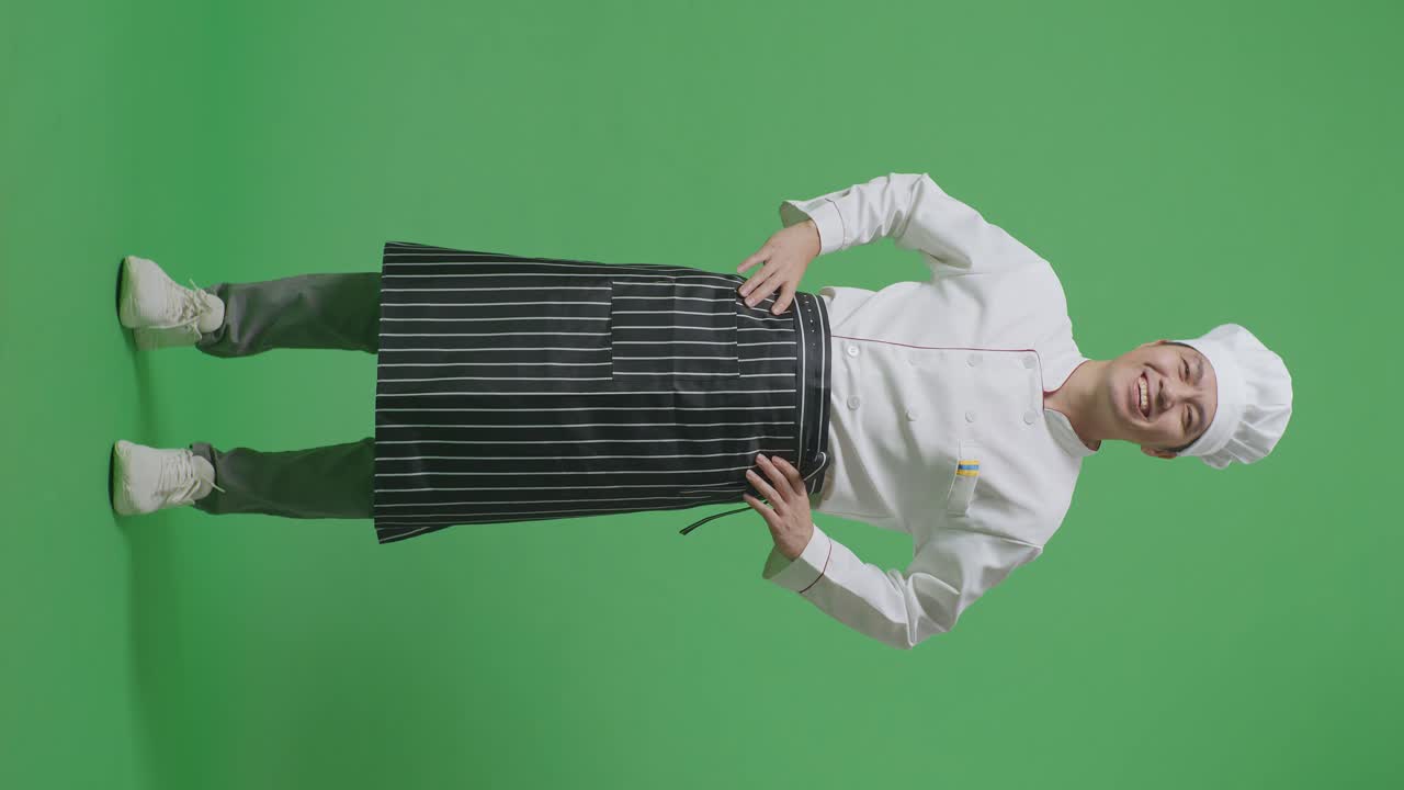 Full Body Of Asian Man Chef With Arms Akimbo Looking At Camera And Smiling While Standing In The Green Screen Background Studio