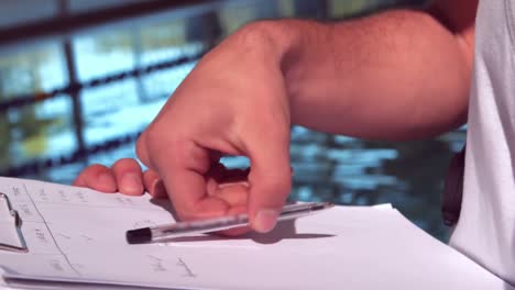 swimming instructor writing on clipboard by the pool