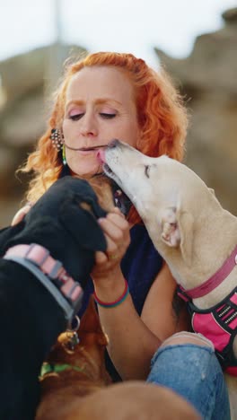 woman showing affection to her dogs outdoors