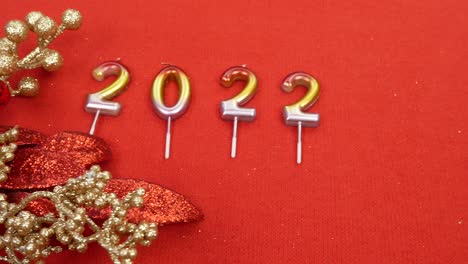 numeral 2022 candles on a red background. near red christmas flower