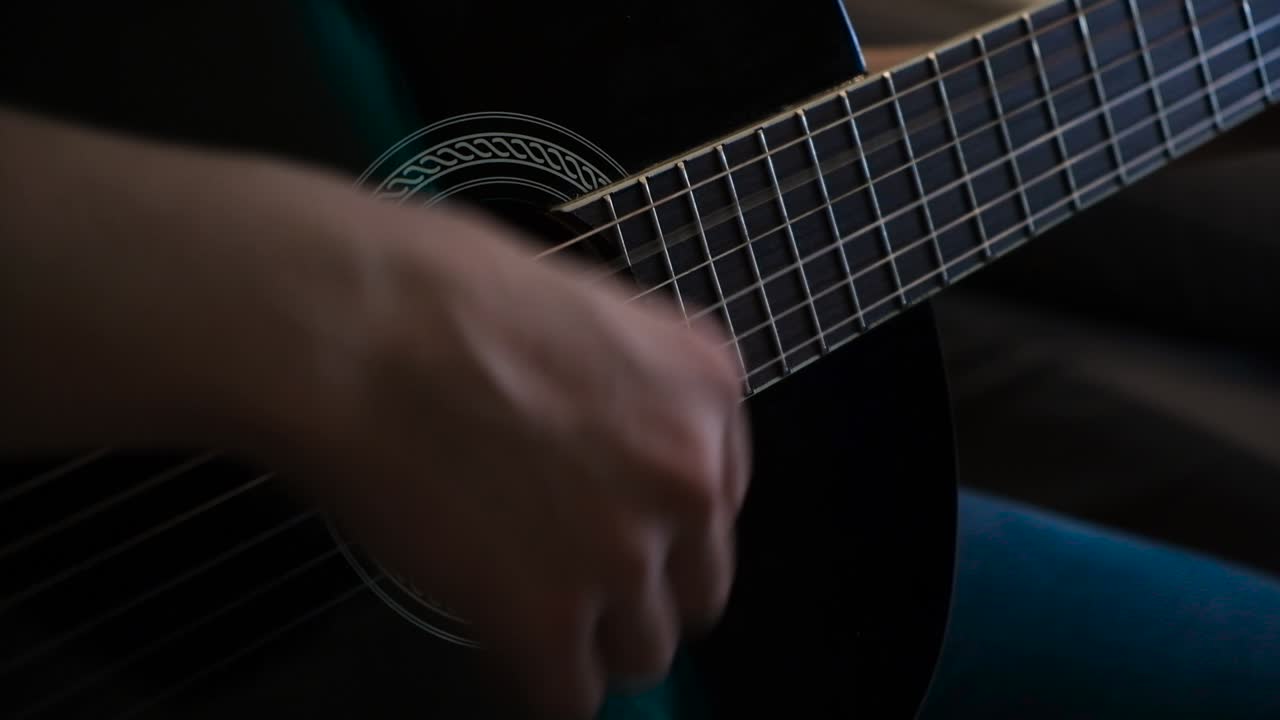 Person som spelar en svart akustisk gitarr