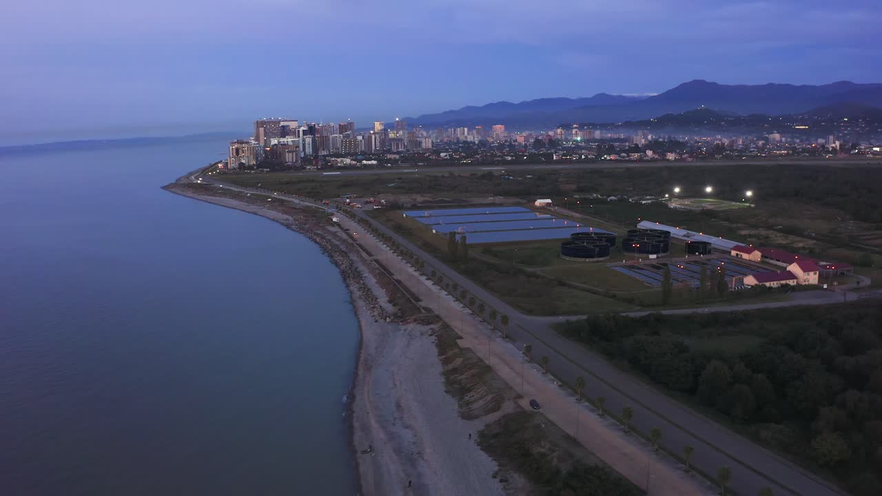 vuelo cinematográfico sobre las instalaciones de tratamiento de aguas residuales en la orilla del mar al amanecer después de la colorida puesta de sol, batumi, georgia