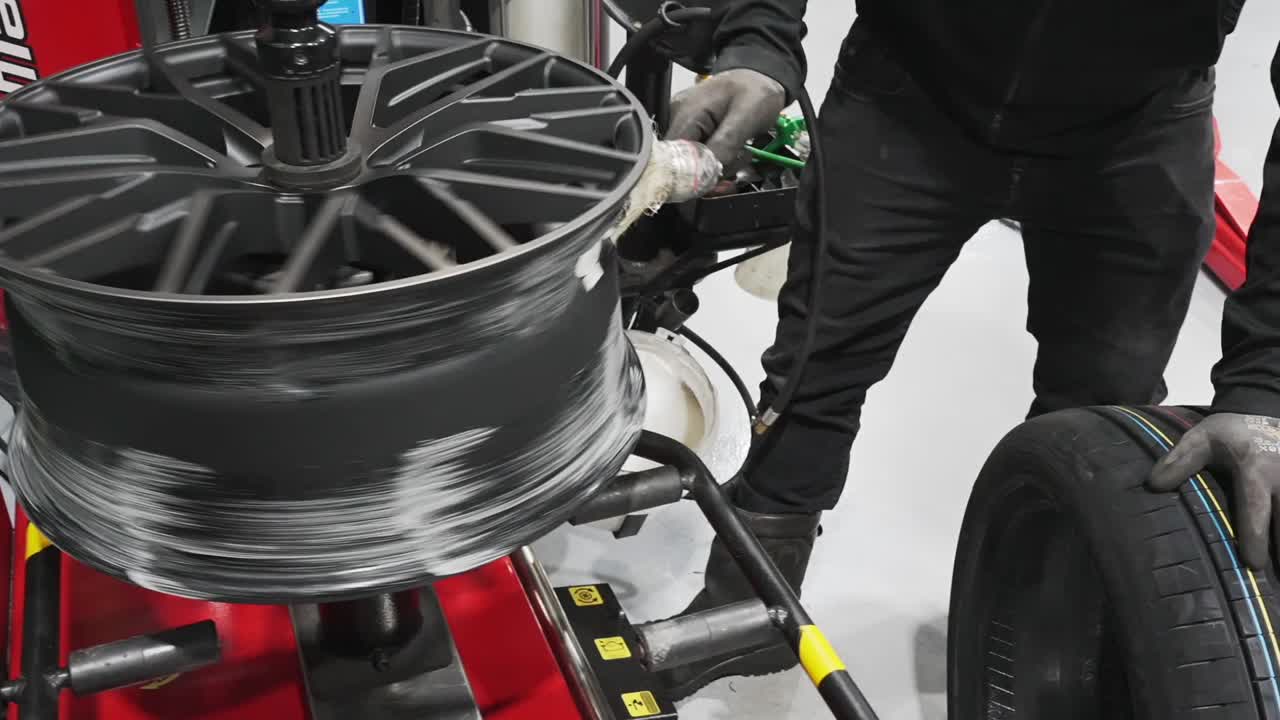 mecánico de automóviles poniendo lubricante líquido de montaje de neumáticos en la rueda de aleación de aluminio, cinematográfico