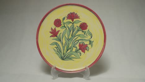 decorative ceramic plate with floral design and vibrant colors presented on stand.