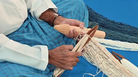 an arab fisherman is weaving a fishing net in an old, traditional way