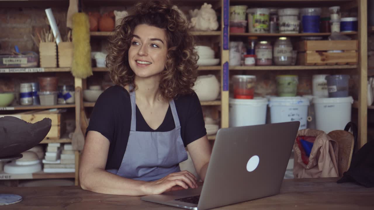 Donna ceramista che usa il laptop in uno studio d'arte.