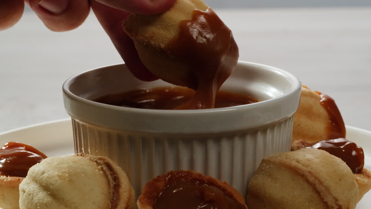 집에서 만든 견과류 모양의 쿠키와 여진 응축 우유가 회색 테이블에 평평하게 놓여 있습니다. 고품질의 4k 영상