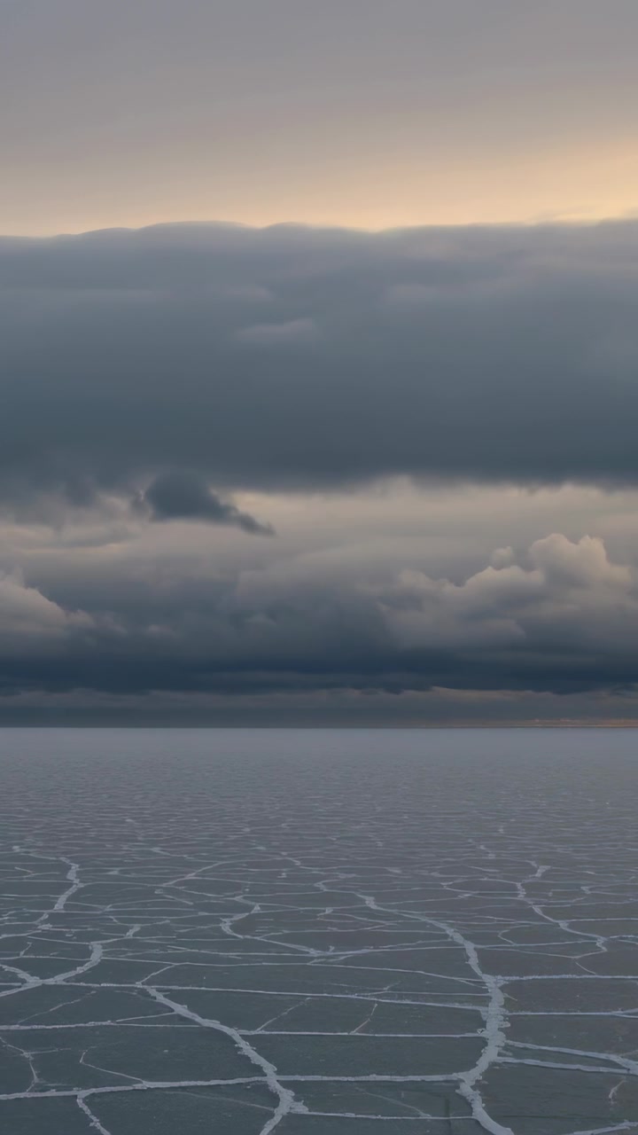 Vertical video: Glowing horizon causing low cloud bank shifting over fractured sea ice with leads