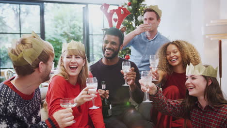 portrait of friends celebrating with champagne after christmas dinner making a toast to camera