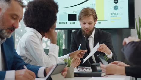 apuesto sonriente confiado experimentado jefe barbudo discutiendo informe junto con la mujer de piel negra subordinada durante la reunión en la sala de oficina