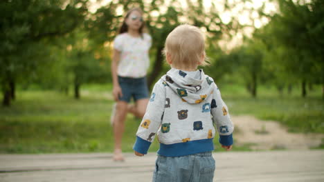 toddler copying sister movements outdoors. teen girl dancing with little brother