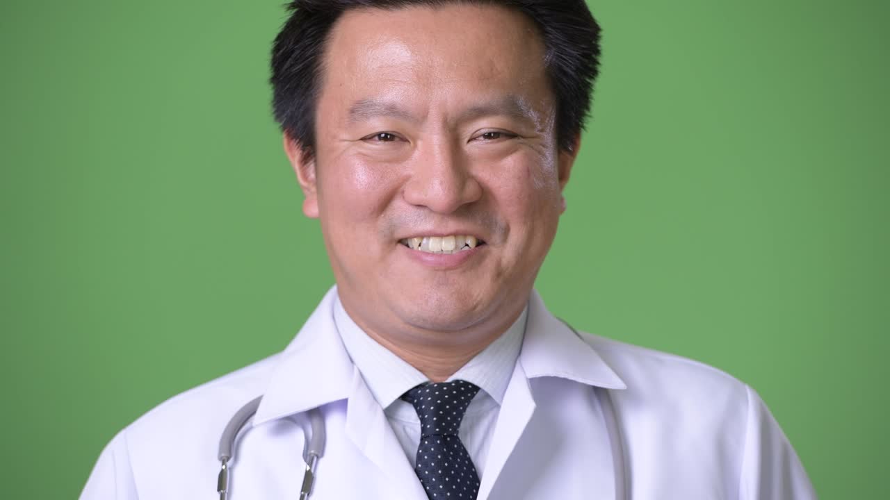 성숙한 일본인 남성, 초록색 배경의 의사