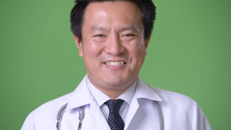 성숙한 일본인 남성, 초록색 배경의 의사