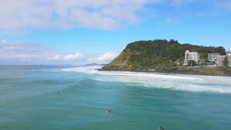 surfers at the beach with the famous burleigh heads in australian city of gold coast at daytime