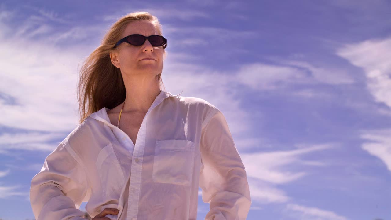 cinemagraph de una mujer bonita y sexy mirando hacia afuera frente a un cielo en movimiento.