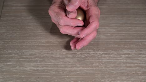 old man hands reveal a golden egg where his hands serve as a nest