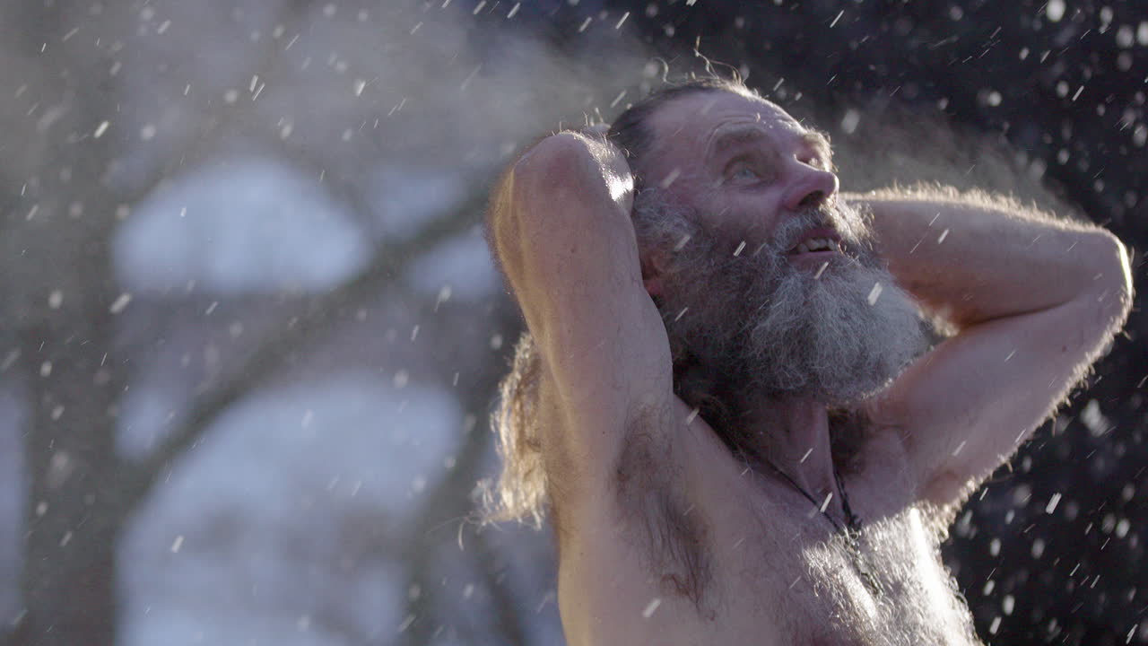 Steam rising from man after sauna standing in snowfall looking up talking to God