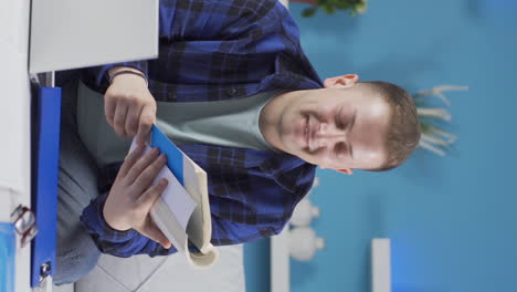 Vertical-video-of-Home-office-worker-man-reading-a-book.