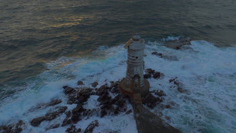 faro de mangiabarche: vista aérea en órbita del hermoso faro y con las olas golpeando
