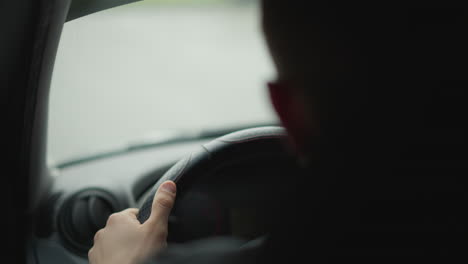 back view of urban explorer driving with hands on steering wheel, interior shot framed to emphasize control and focus during chilly city commute, blurred street scene beyond windshield adds mood