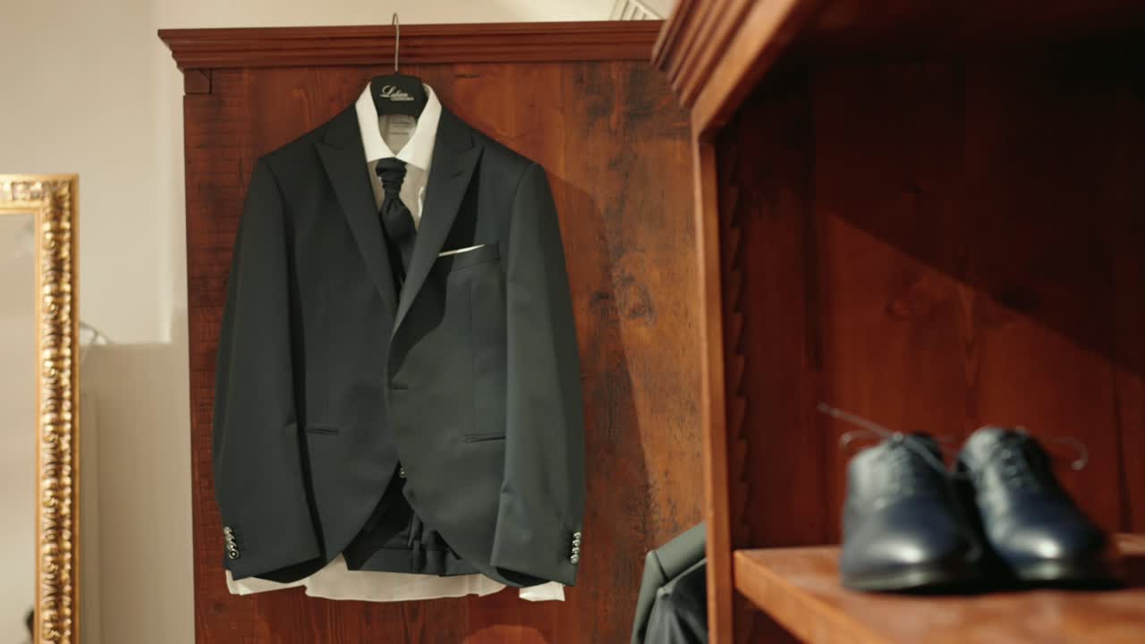 전경에 있는 나무 벽 검은색 가죽 신발에 걸려 있는 검은색 정장