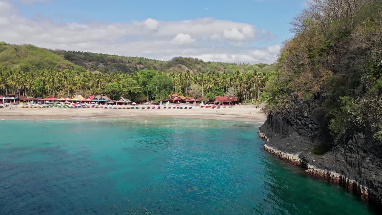 인도네시아 카랑아세미 동부 발리의 절벽 뒤에 있는 해변을 드러낸 드론