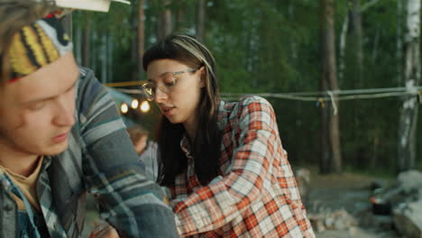 young tourists setting up tent while camping with friends