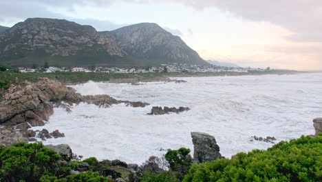 frothing sea water as waves crash into jagged voëlklip coastline in hermanus