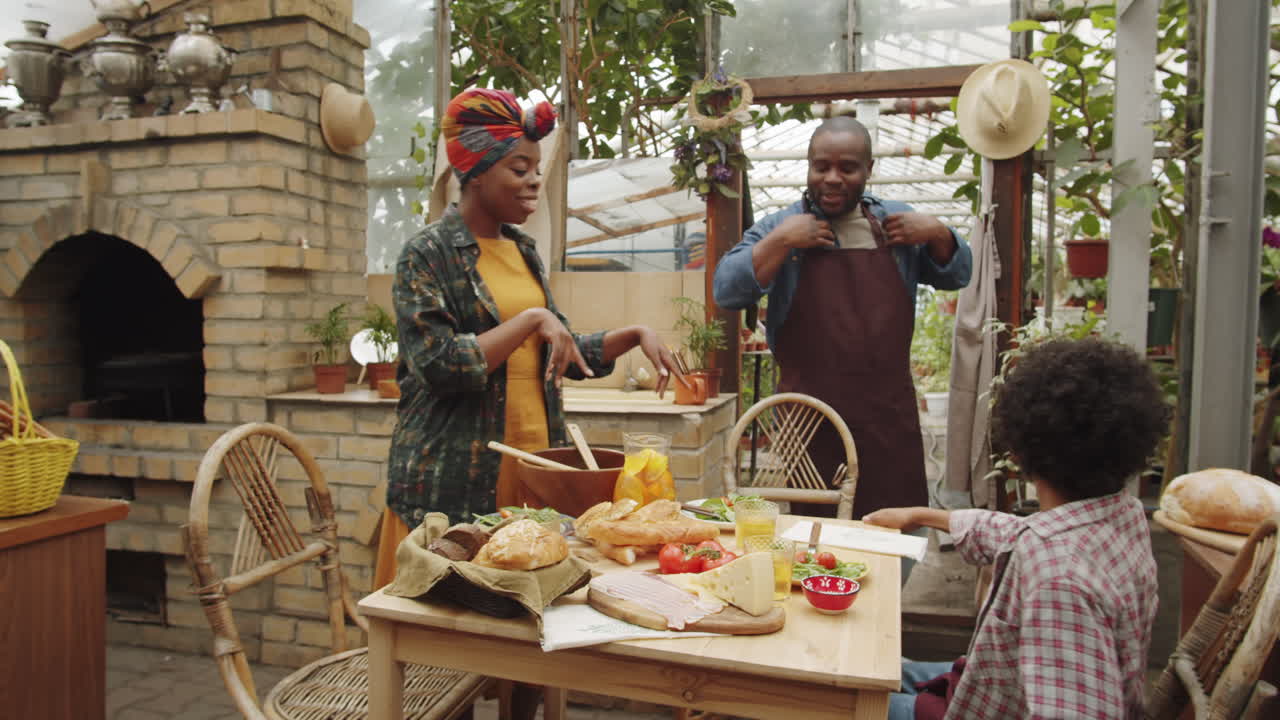 Famiglia afroamericana che si riunisce per cena in serra.
