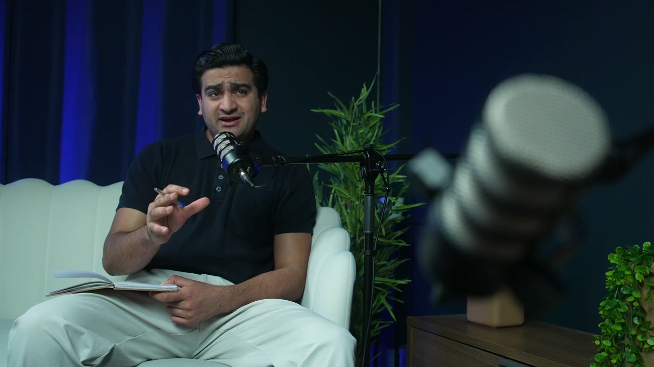 Confident male host or guest talking during a podcast recording in a professional studio setup with microphones. media, communication, and digital content concepts