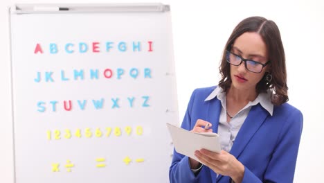 woman teacher instructing with alphabet and numbers on whiteboard