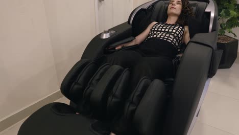 a lady relaxing in a massage chair - handheld pullback shot