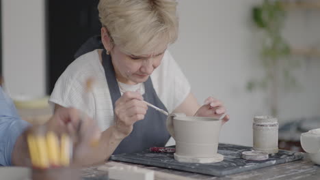 mujer alfarera sujetando el mango a la taza en el estudio de cerámica. mujer alfarera dando forma y tallando la taza en el estudio del taller de cerámica