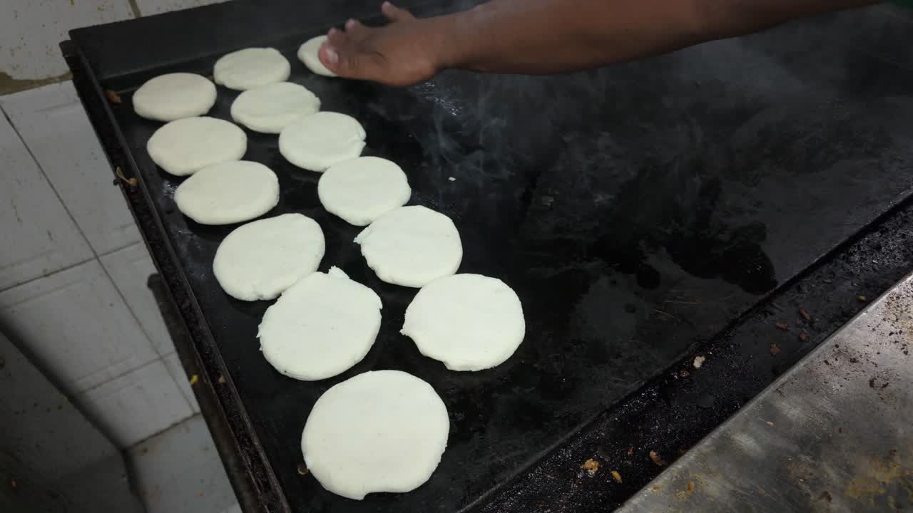 Hot griddle with arepas cooking, creating a tasty and warm feeling