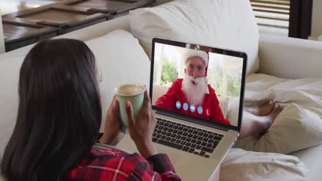 Mujer-De-Raza-Mixta-En-Videochat-Portátil-Tomando-Café-Durante-La-Navidad-En-Casa