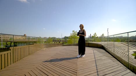 mujer tomando fotos y caminando por un puente de madera en un parque