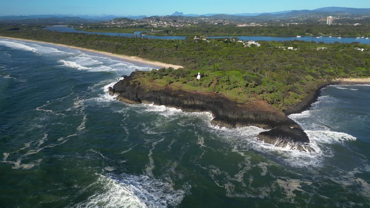 Right to left rotating aerial looking at Fingal Head Lighthouse from over the ocean on a sunny day, Northern New South Wales, Australia.