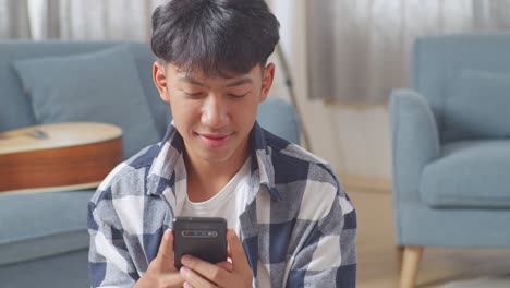 아시아 십대 부부의 근접 사진, 집으로 돌아온 소녀가 스마트폰으로 바닥에 앉아있는 남자친구를 놀라게합니다.