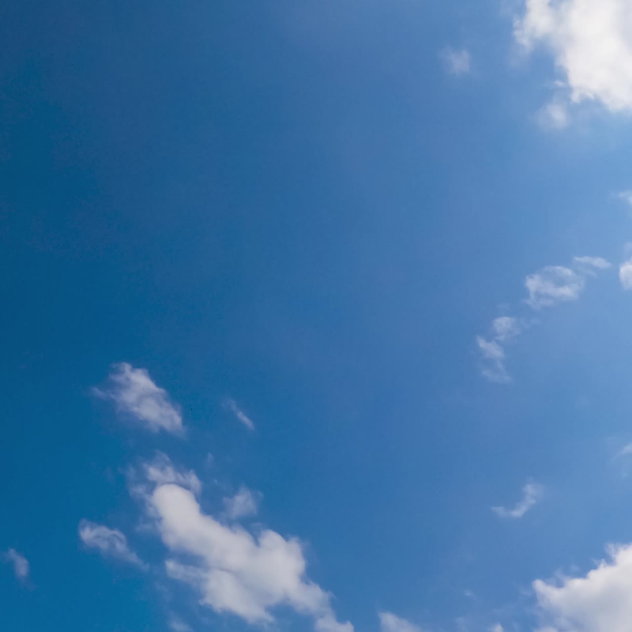 Little light clouds quickly flying by the wind. Cloudscape gathering in the sky. Low angle view. Timelapse