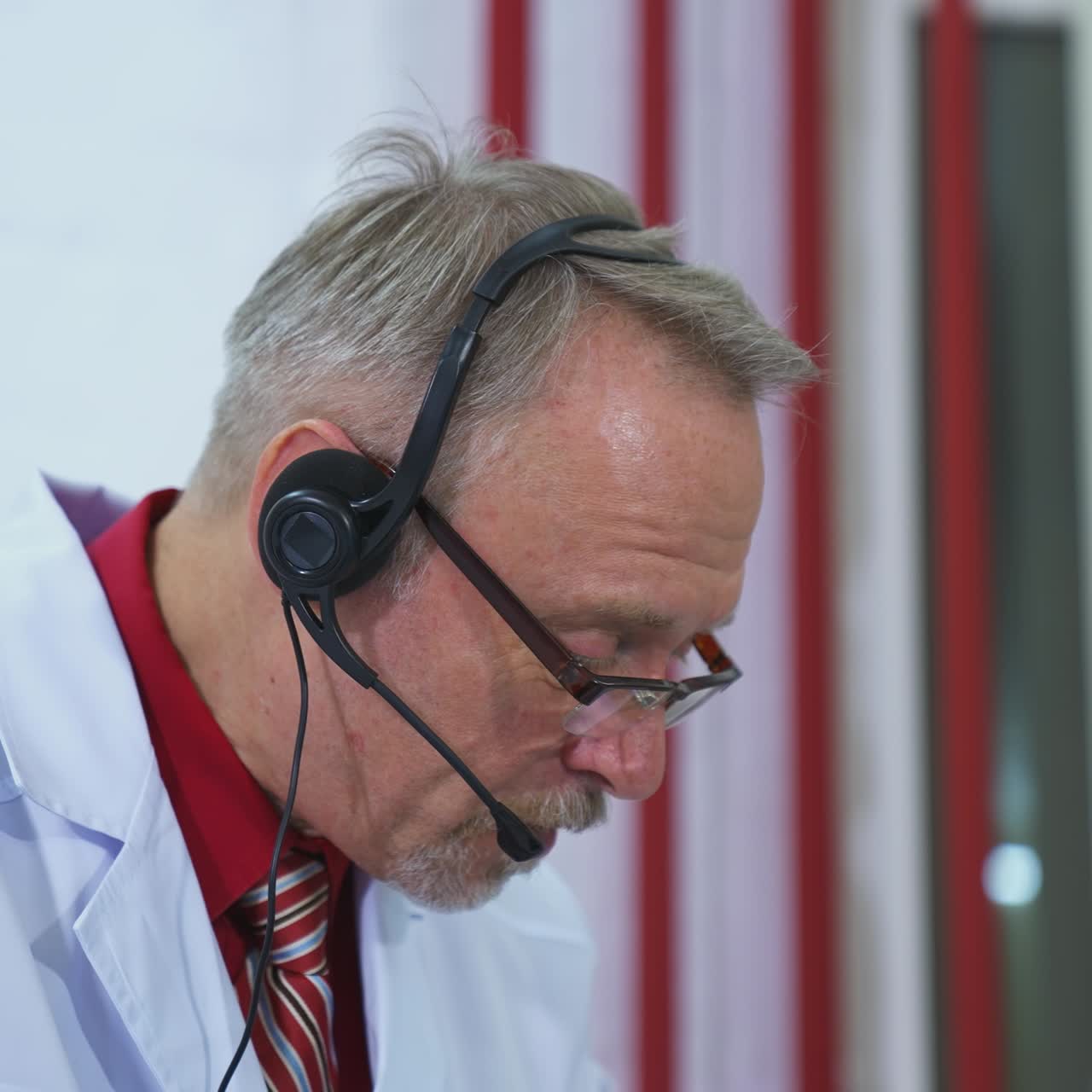 Senior physician talks to camera consulting patient online in web chat. Old adult male doctor wears white medical coat and headset makes distant video call. Telemedicine concept.