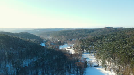 Aufsteigende-Drohnenaufnahme-Einer-Wunderschönen-Winterlandschaft-Mit-Hohen-Bäumen-Und-Berghügeln-Im-Winter