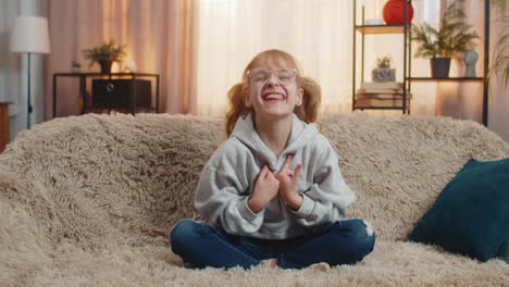 young teenager girl celebrating victory with a joyful smile while looking at camera indoors at home