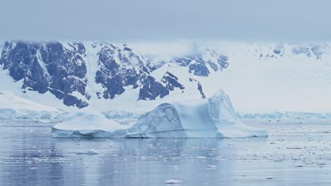 Icebergs-and-Mountains-Scenery-in-Antarctica-Landscape-Scene-with-Big-Dramatic-Ice-Formations,-Global-Warming-and-Climate-Change-on-Coast-with-Ocean-and-Sea-Water-on-Antarctic-Peninsula-in-Winter