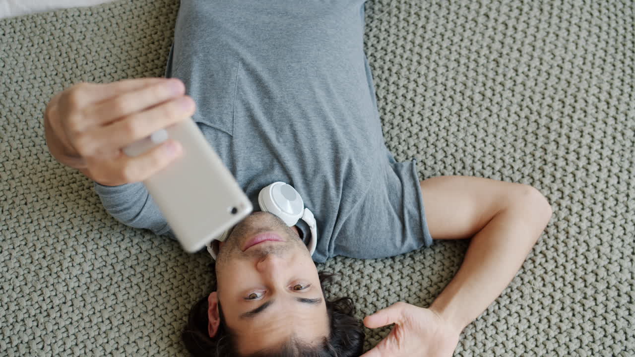 Man taking a selfie while lying on a carpet