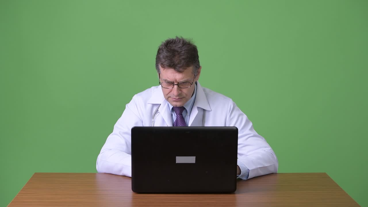 hombre maduro y guapo médico contra fondo verde