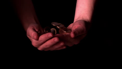 Hands-throwing-coins-and-catching-them-on-black-background