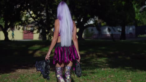 white hair woman walks in a park while holding her roller skates and wearing a mini skirt before turing around