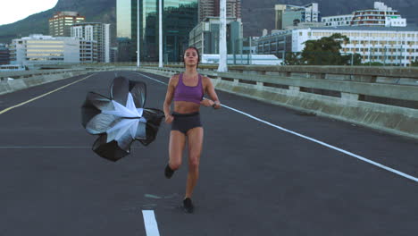 mujer corriendo con paracaídas en un puente de la ciudad