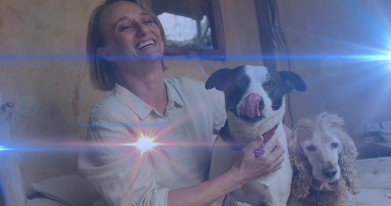 Cão preto e branco cheirando mulher, iniciando um vínculo de cuidado com o animal de estimação, enquanto a mulher abraça o cão e outro cão observa.